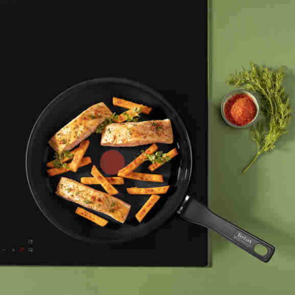Tefal Renew Black koekenpan 24 cm in huiselijke keukenomgeving, getoond naast andere keukenapparatuur om veelzijdigheid te
